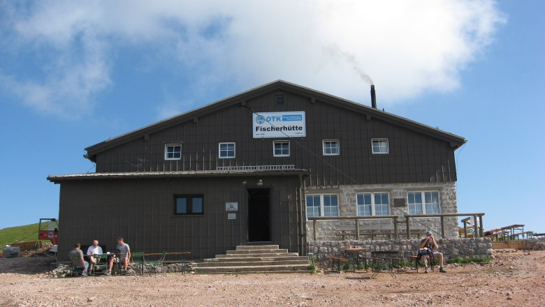 A large building with the inscription 'Fischerhütte' against a blue sky.