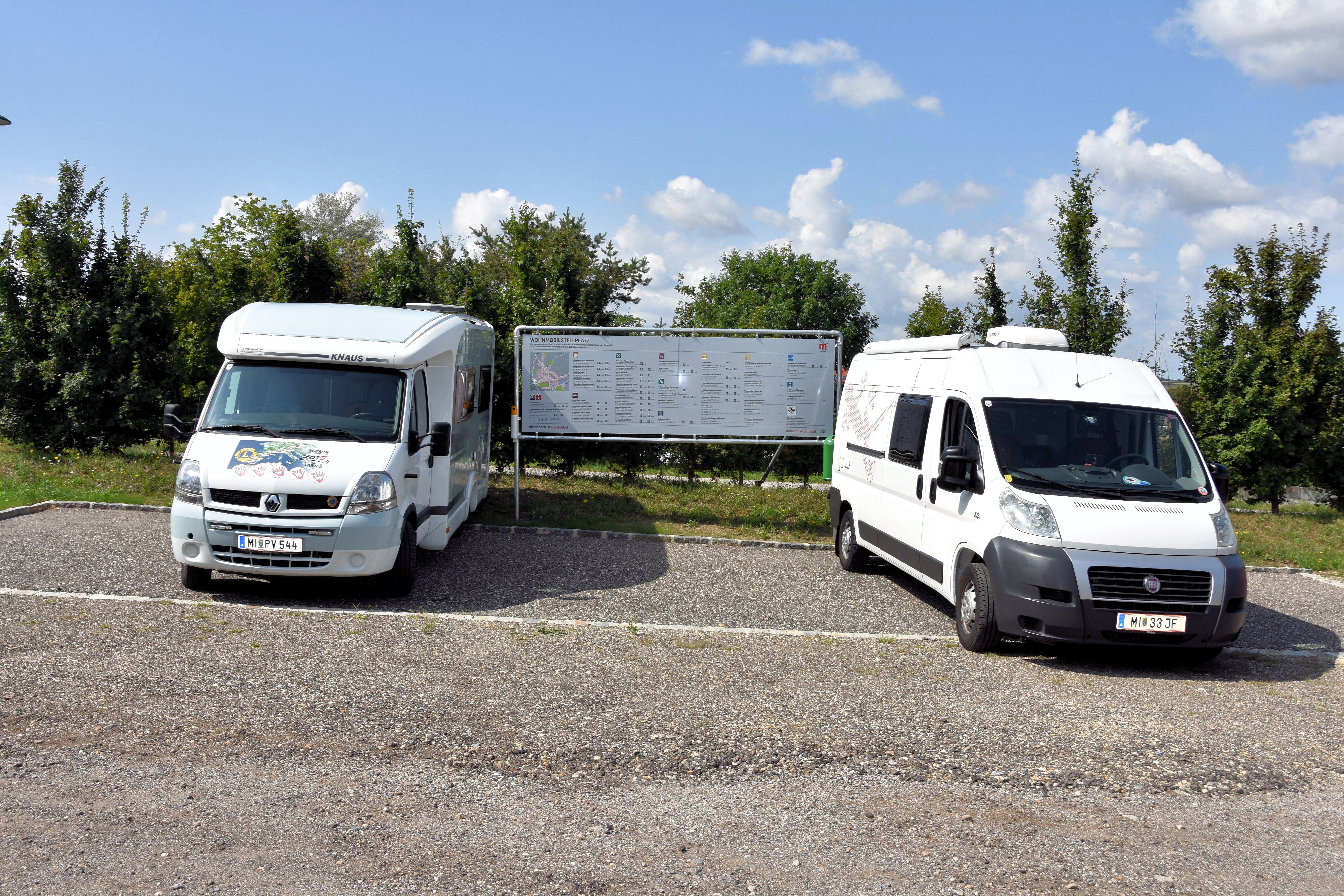 Two mobile homes on a pitch with an information board in the background.