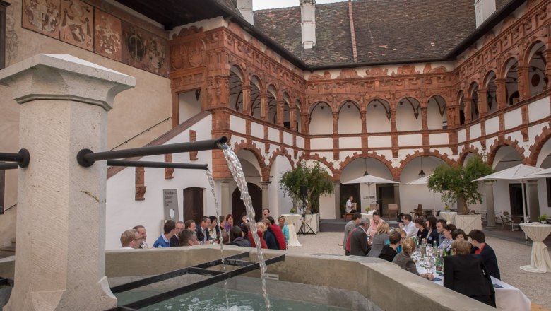 Inner courtyard with fountain, dining guests and impressive architecture on the interior walls.