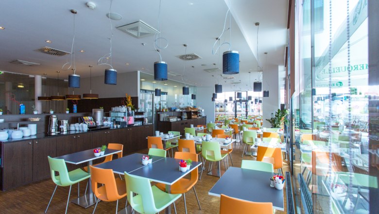 Modern breakfast room with colorful chairs and laid tables.
