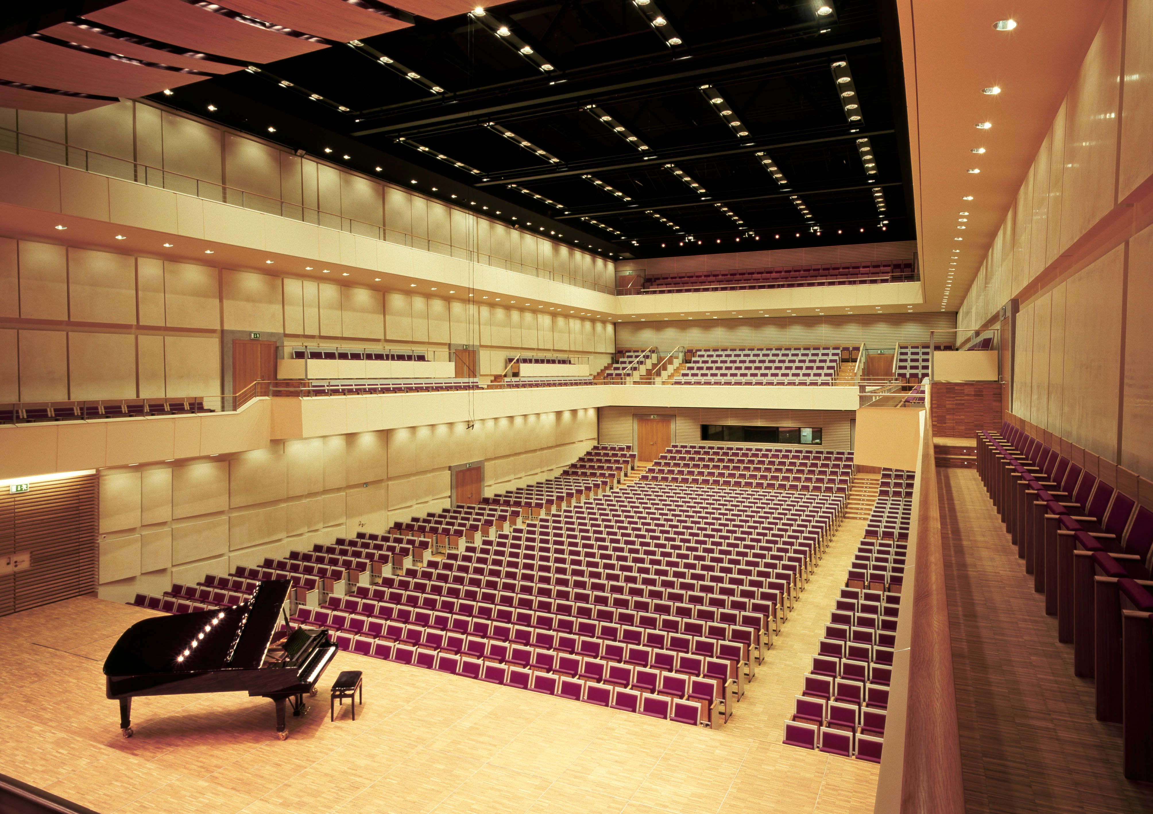 Interior view of the auditorium in Grafenegg Castle with empty rows of seats and a grand piano on the stage.