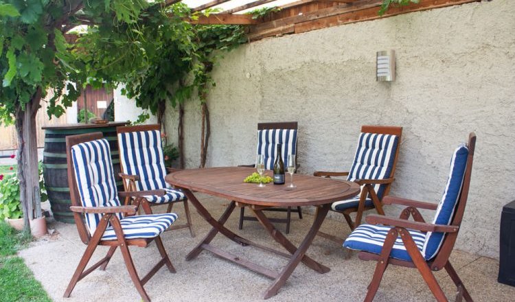 Garden furniture under a pergola with vines.