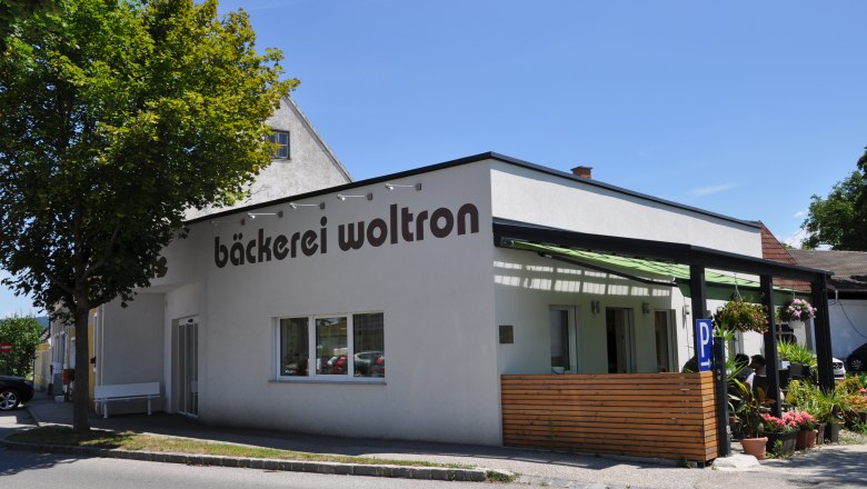 Exterior view of the Woltron bakery with plants and parking lots.
