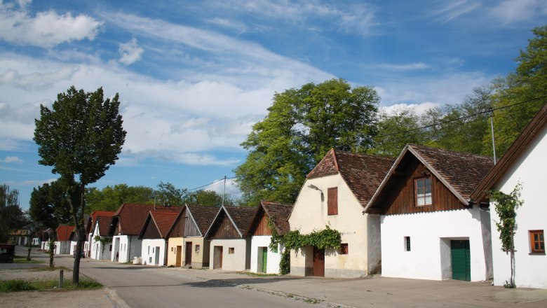 Row of traditional wine cellars in Jetzelsdorf under a blue sky.