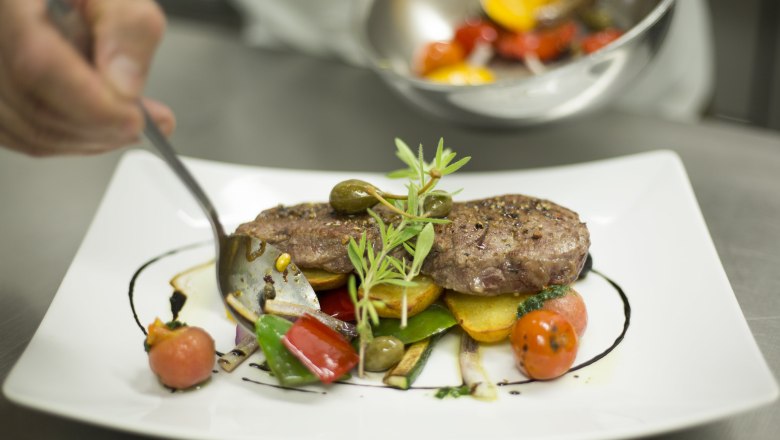 A plate of artfully arranged meat, vegetables and herbs.