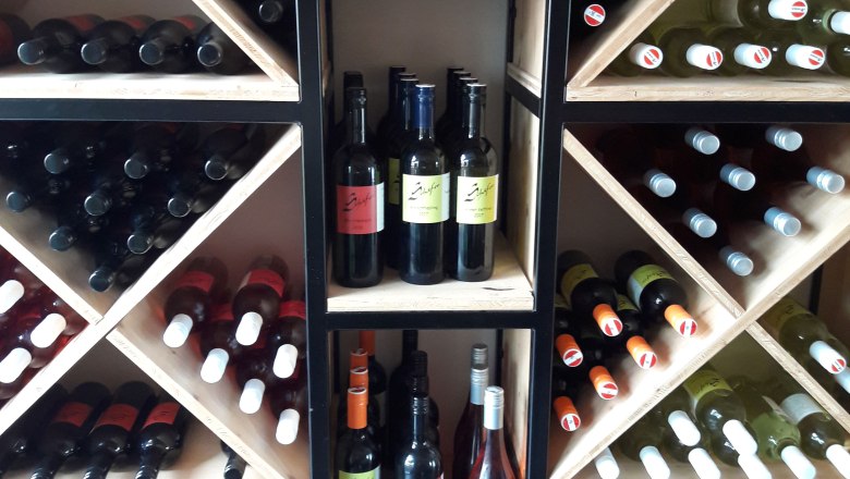 Wine bottles in a wooden rack with diagonal shelves.