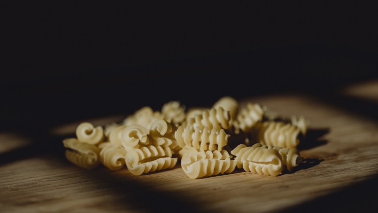 Close-up of uncooked, spiral-shaped noodles on a wooden base.