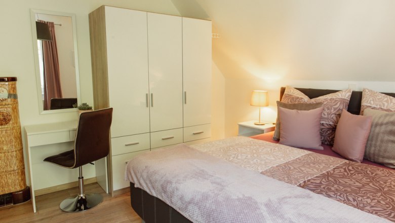 Bedroom with double bed, closet, dressing table and lamp.