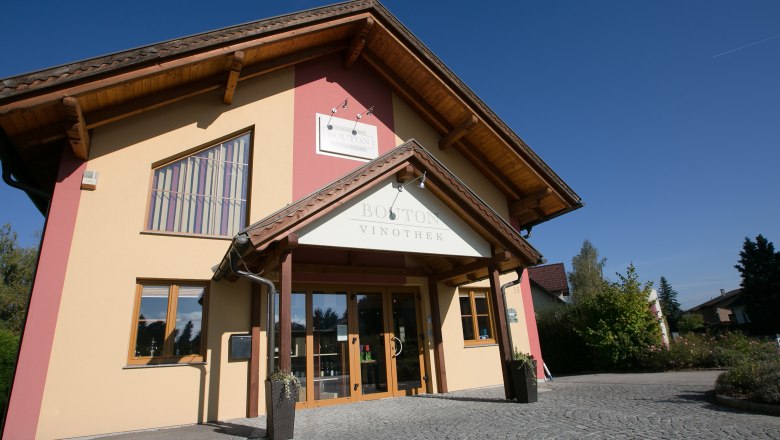 Entrance to the Bouton wine shop with yellow fa&ccedil;ade and wooden roof.