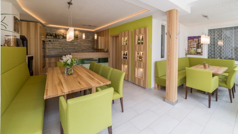 Modern tasting room with wooden tables and green upholstered furniture.