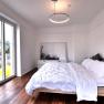 Modern bedroom with large window, wooden floor and double bed.
