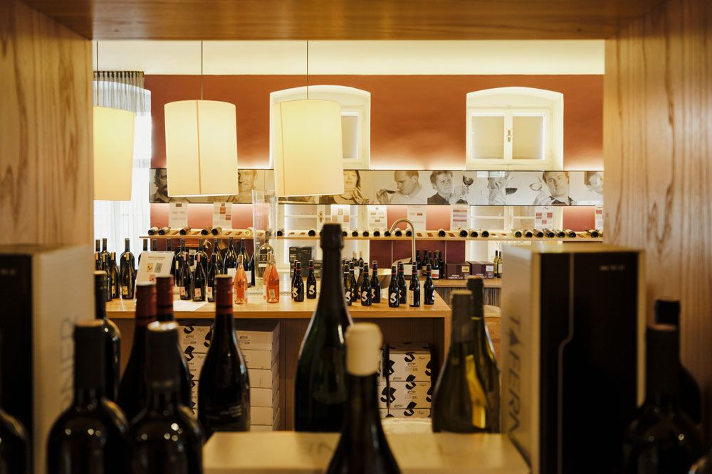 Interior view of a wine shop with wine bottles and decorative lamps.