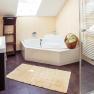 Modern bathroom with bathtub, towel rail and skylight.