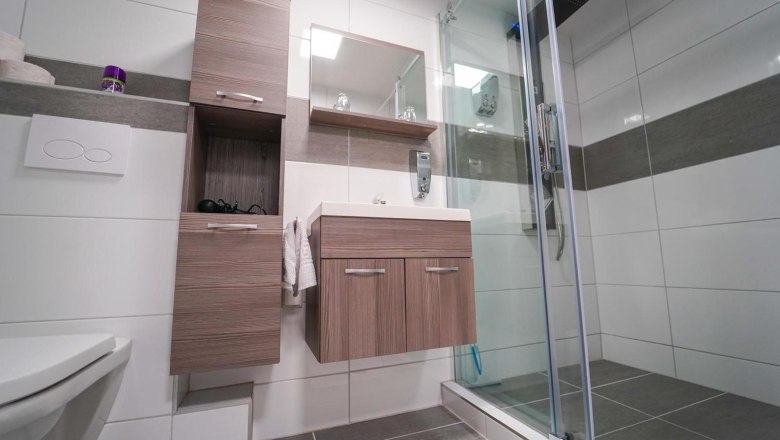 Modern bathroom with shower, washbasin and wooden cabinets.
