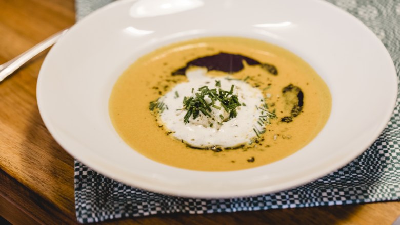A plate of cream of pumpkin soup garnished with cream and herbs.