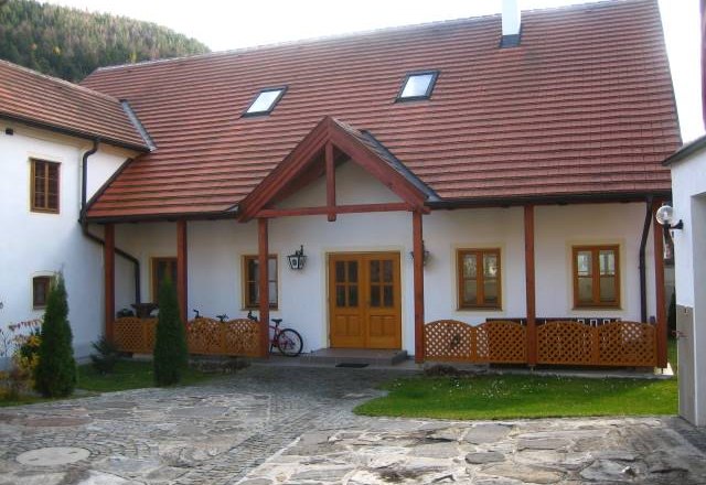 A traditional building with a red tiled roof and wooden elements, surrounded by a paved courtyard.
