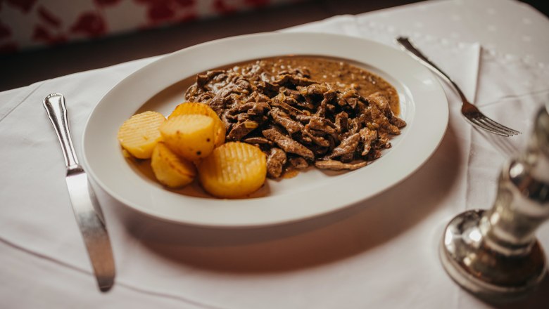 A plate of roasted liver and potatoes on a table.