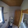 Bathroom with toilet, wooden ceiling and window with blue curtain.