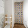 Modern bathroom with patterned tiles in the shower, towel rail and shelf.