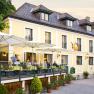 A yellow country inn with a terrace and parasols where people are sitting.