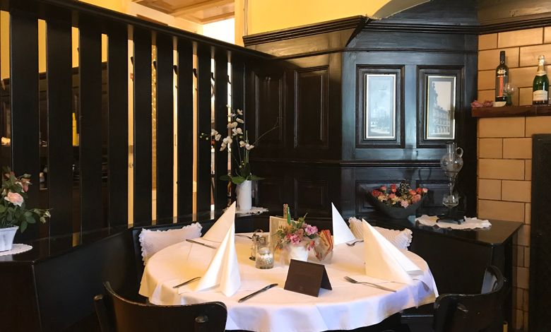 A cozy table in a traditional restaurant with dark wood paneling and decorative flowers.