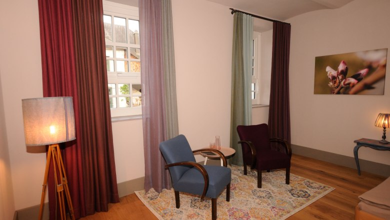 Cozy room with two armchairs, colorful curtains and a carpet.