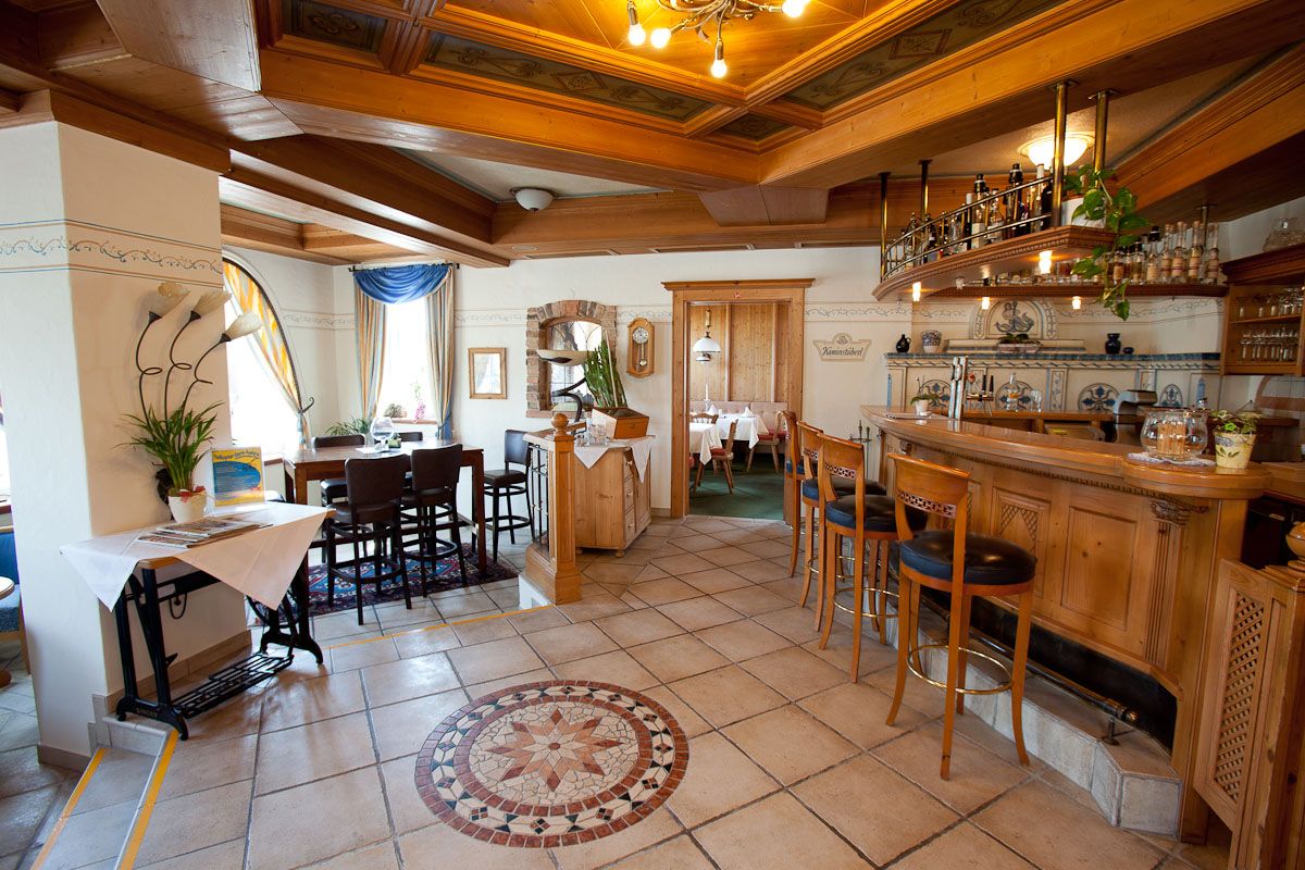 Cozy hotel bar with wooden furniture and decorative tiled floor.