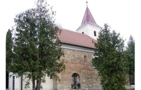 Historic church with red roof and tower, surrounded by trees.