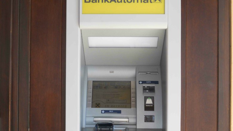 An ATM with a yellow sign and Raiffeisen logo.