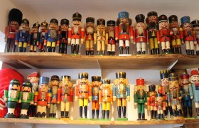 A collection of colorful nutcracker figures on two wooden shelves.