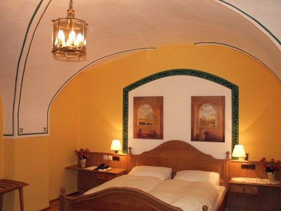 Cozy bedroom with wooden bed, yellow walls and vaulted ceiling.