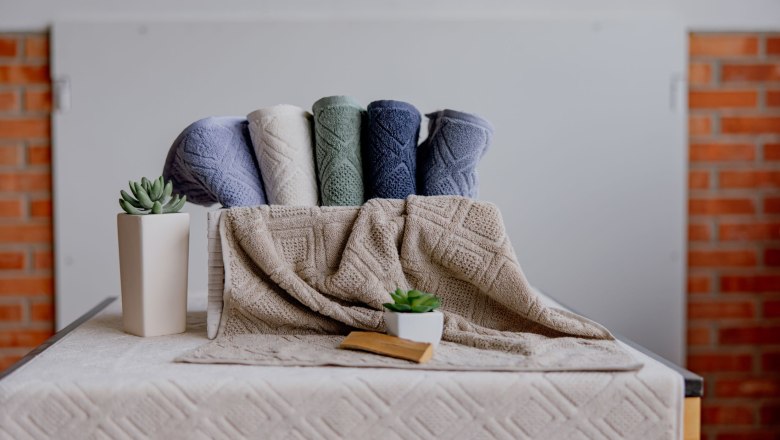 Colored towels and plants on a table in front of a brick wall.