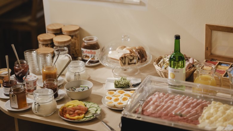 Breakfast buffet with bread, cold cuts, fruit and drinks.