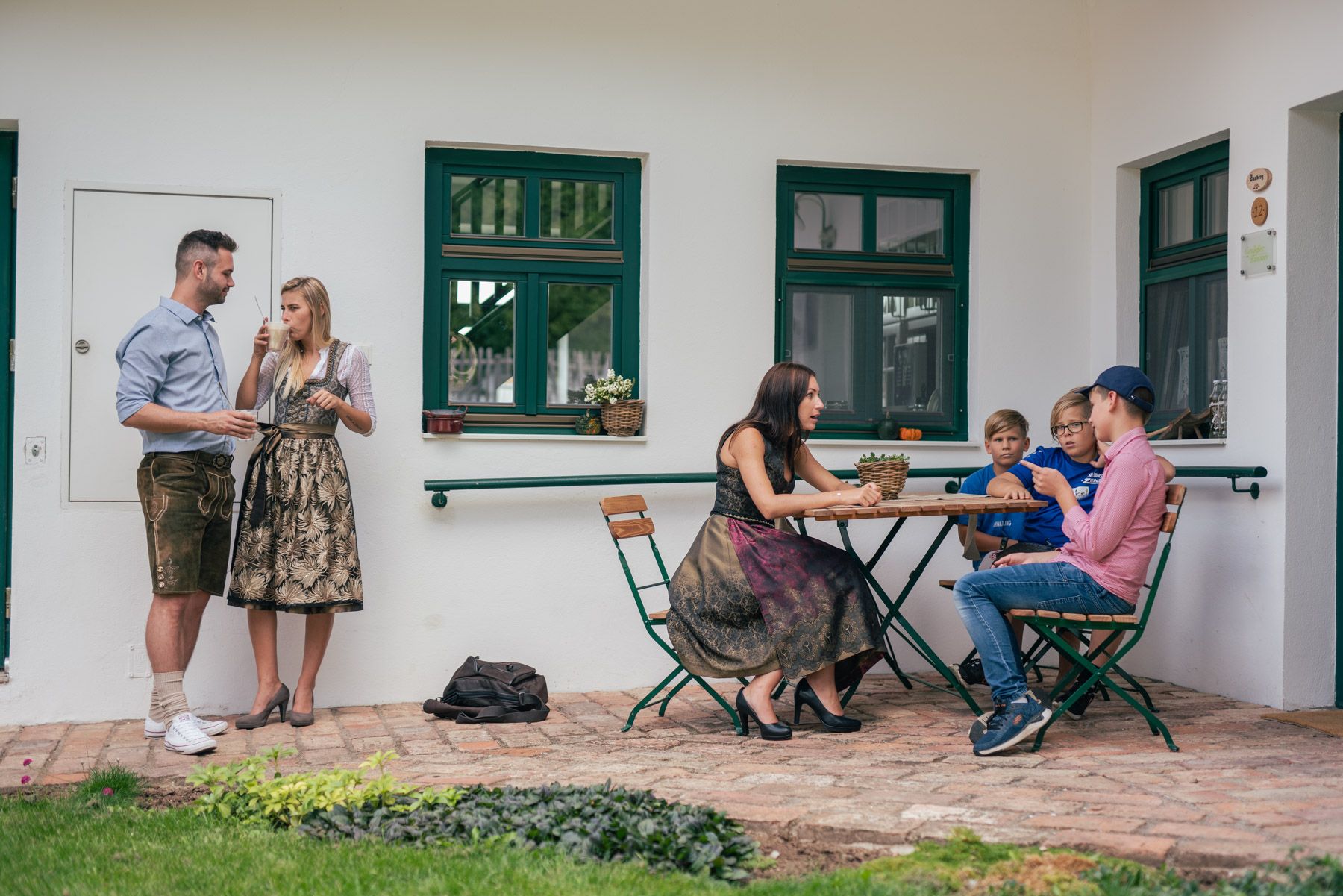 People in traditional dress on a vineyard, some standing, others sitting at a table.