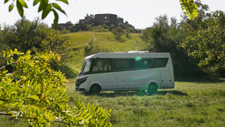 Motorhome on a meadow in front of a castle ruin in Falkenstein.