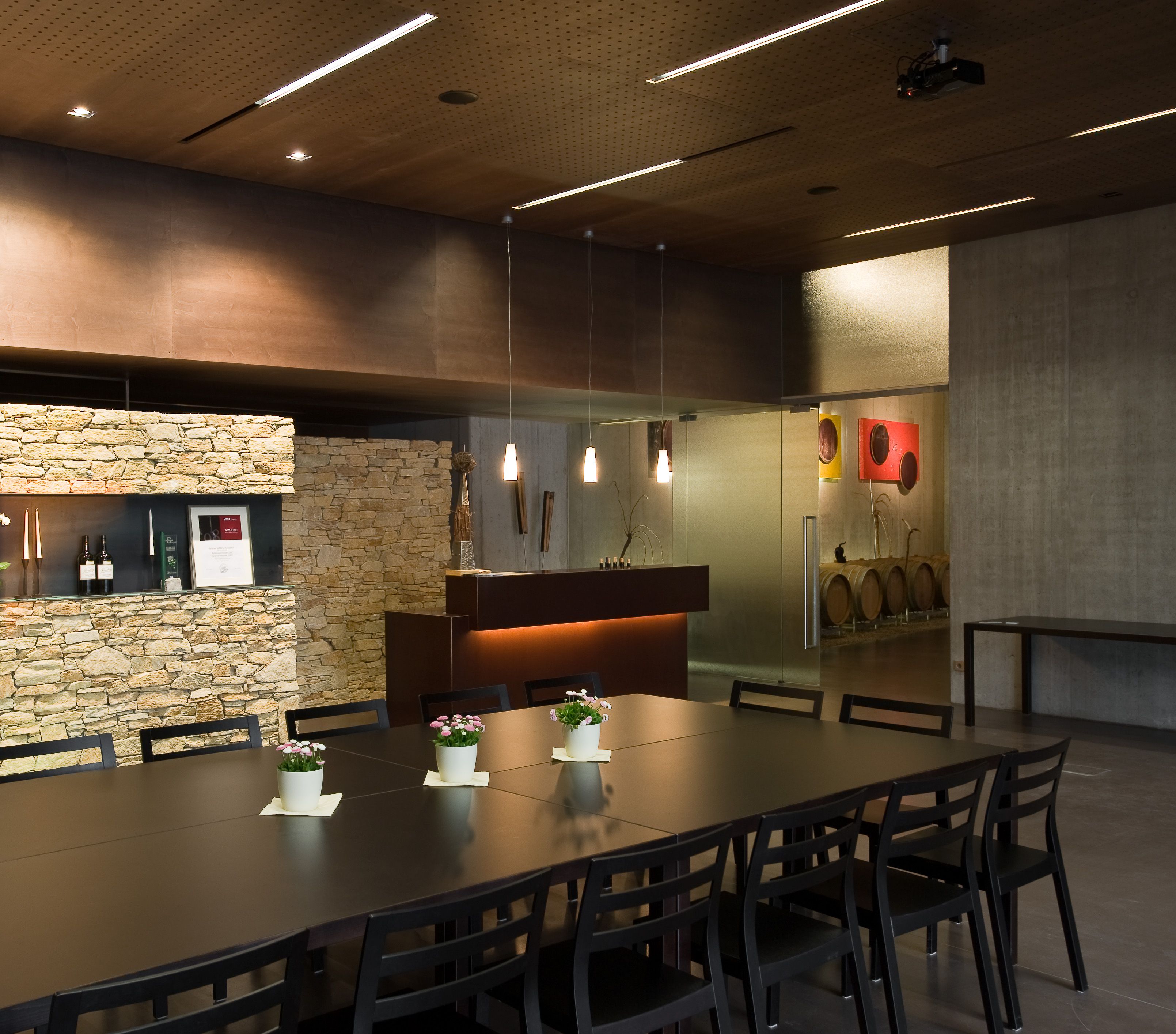 Modern tasting room with wooden table, chairs and stone wall.