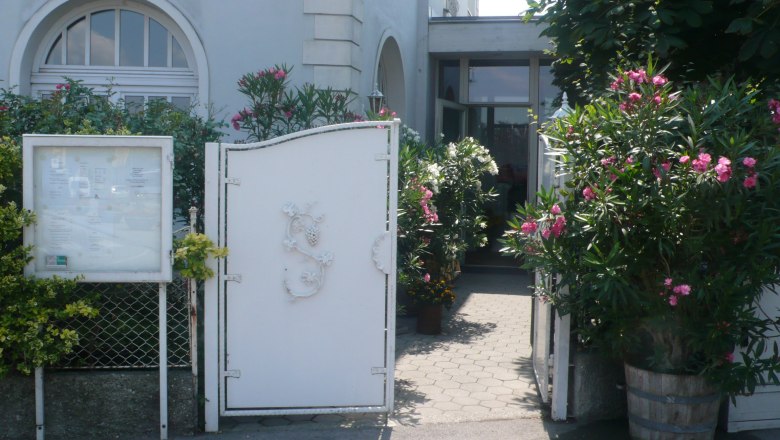 Entrance with white gate and flowering oleander plants.