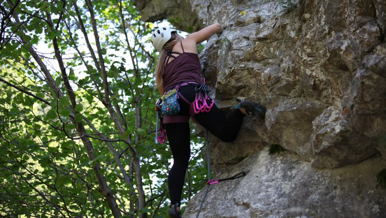 Person climbing on a rock face in the forest.