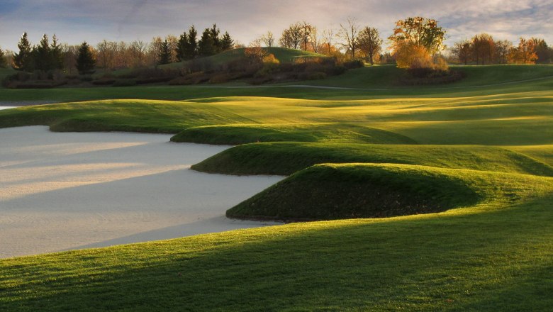 Panorama of a golf course with sand bunkers and green hills in the sunlight.
