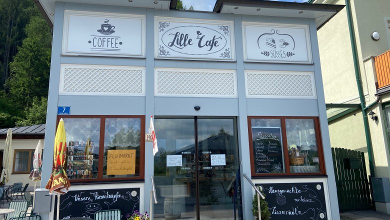 Exterior view of a café with signs for coffee and sweets.