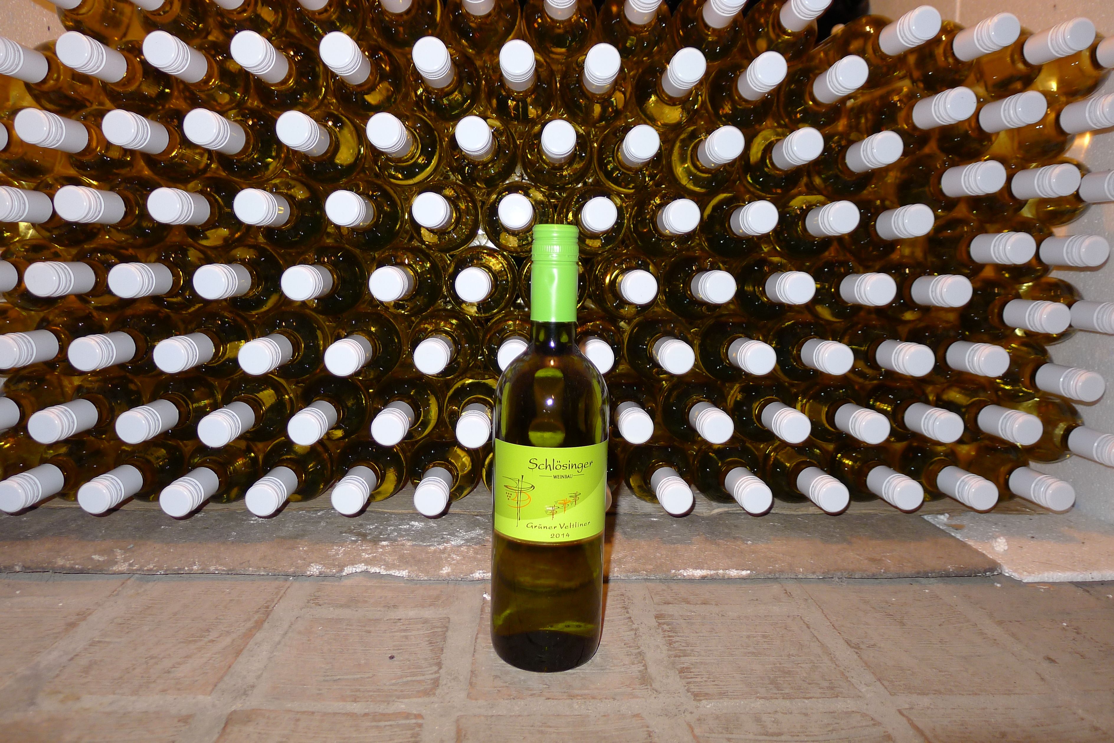 A bottle of Grüne Veltliner in front of a shelf full of wine bottles.