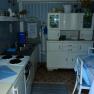 Small, cozy kitchen with blue and white decoration, a stove, sink, cupboard and small dining table.