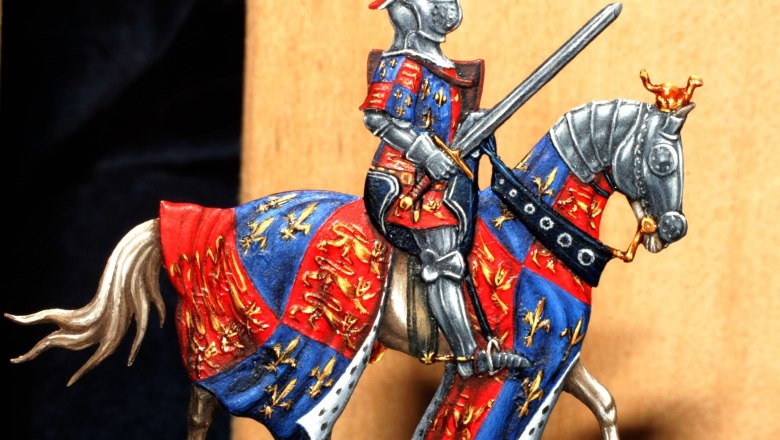 Pewter figure of a knight in armor on a horse with a colorful tabard.