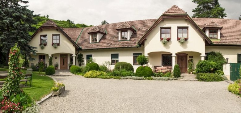A traditional country house with a well-kept garden and gravel path.