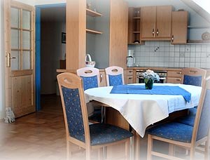 Dining area of a vacation apartment with wooden furniture and blue tablecloth.