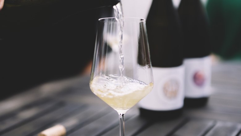 White wine is poured into a glass on a table.