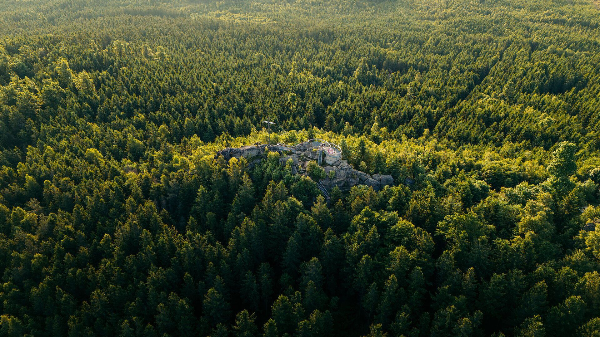 Viewing platform on a rock formation with a bird's eye view over densely wooded hills in the Waldviertel.