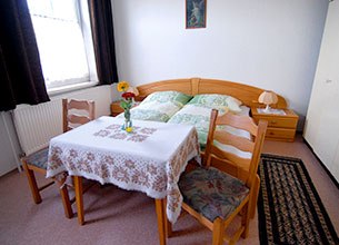 Cozy room with double bed, table, two chairs and flowers.