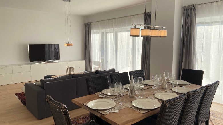 Modern living/dining area with dining table, chairs, sofa and TV.