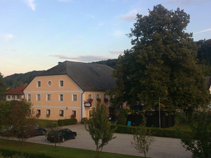 View of a yellow inn with a large tree and parking lot.